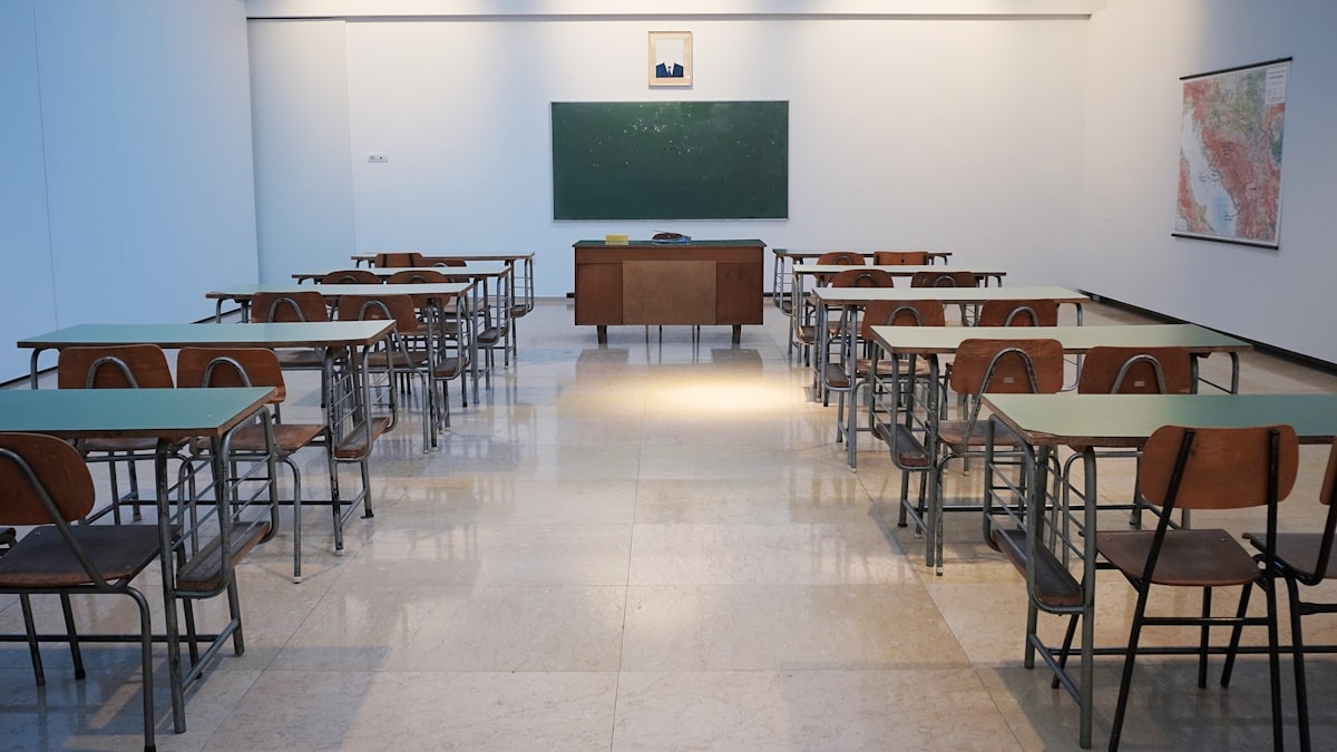 Sala de aula com carteiras alinhadas e quadro verde ao fundo