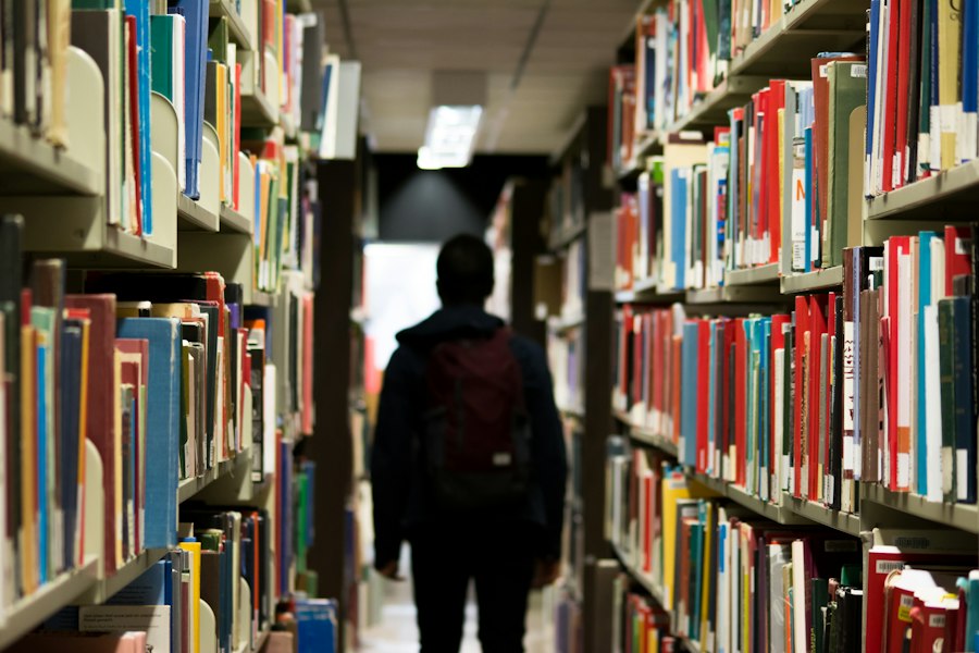 Estudante caminhando entre estantes de livros em uma biblioteca