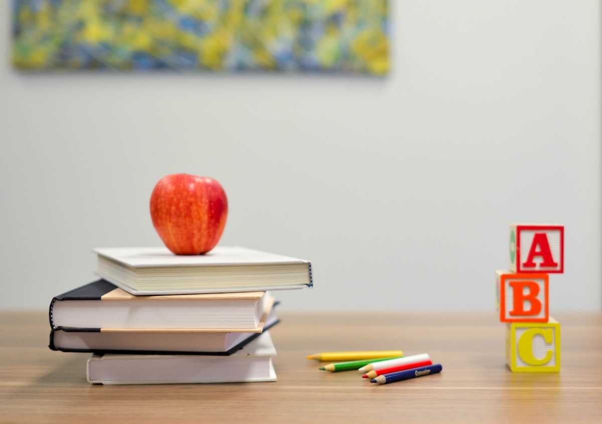 Livros, lápis de cor e cubos com as letras A, B e C sobre uma mesa